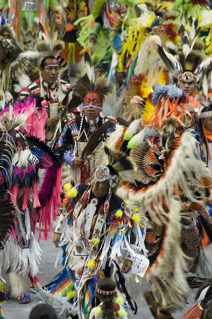 Ein Native American nimmt an einem traditionellen Sonnentanz teil, gekleidet in traditionelle Kleidung und mit Federn im Haar. Die Zeremonie symbolisiert die tiefe spirituelle Verbindung zur Natur und den Ausdruck von Gemeinschaft und kultureller Tradition.